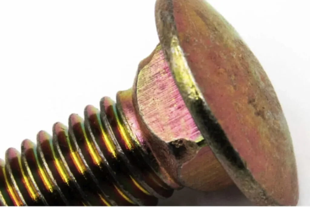Closeup image of the head of a bolt that has yellow zinc coating (Zinc Chromate Coating)